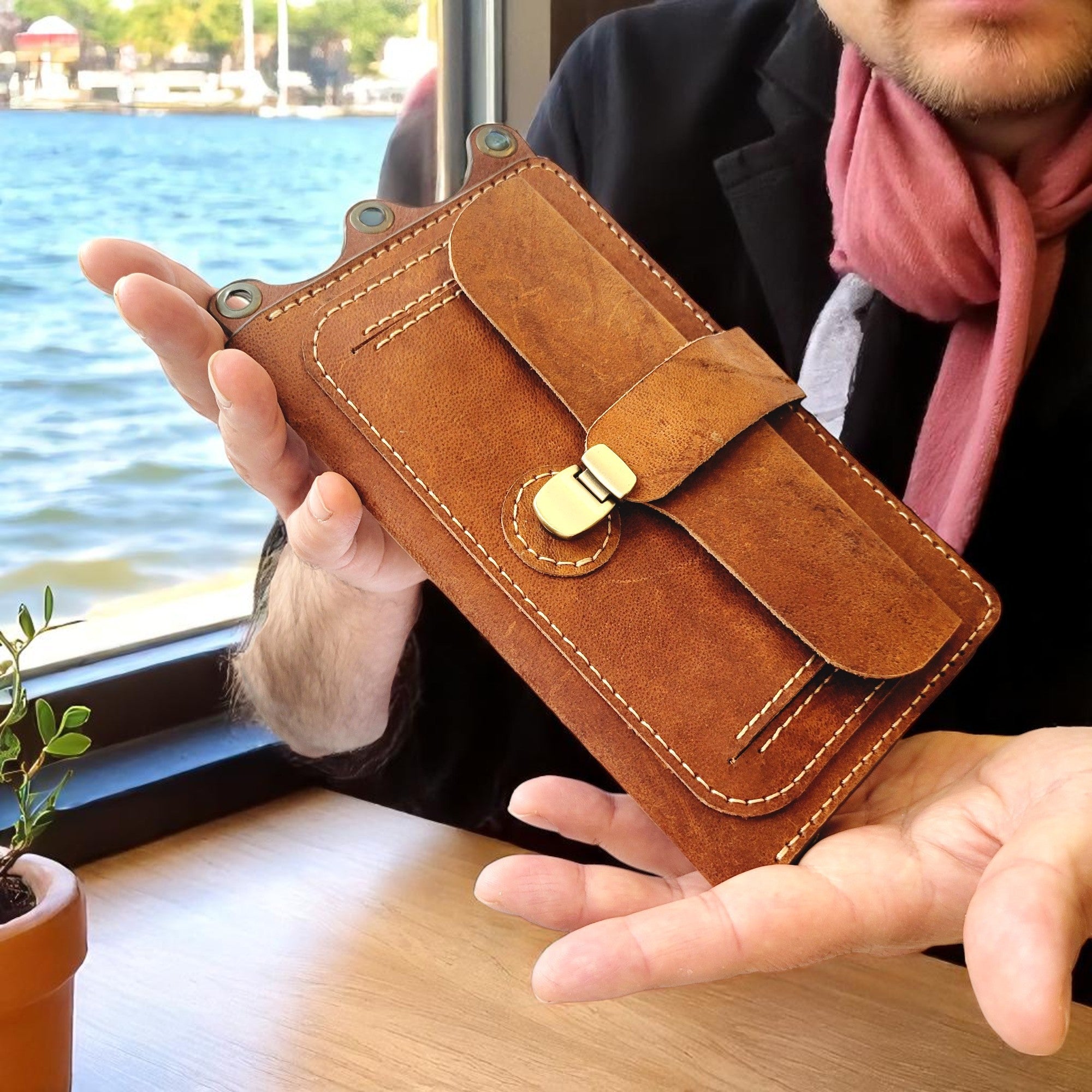 Person holding a brown leather wallet with a scenic background