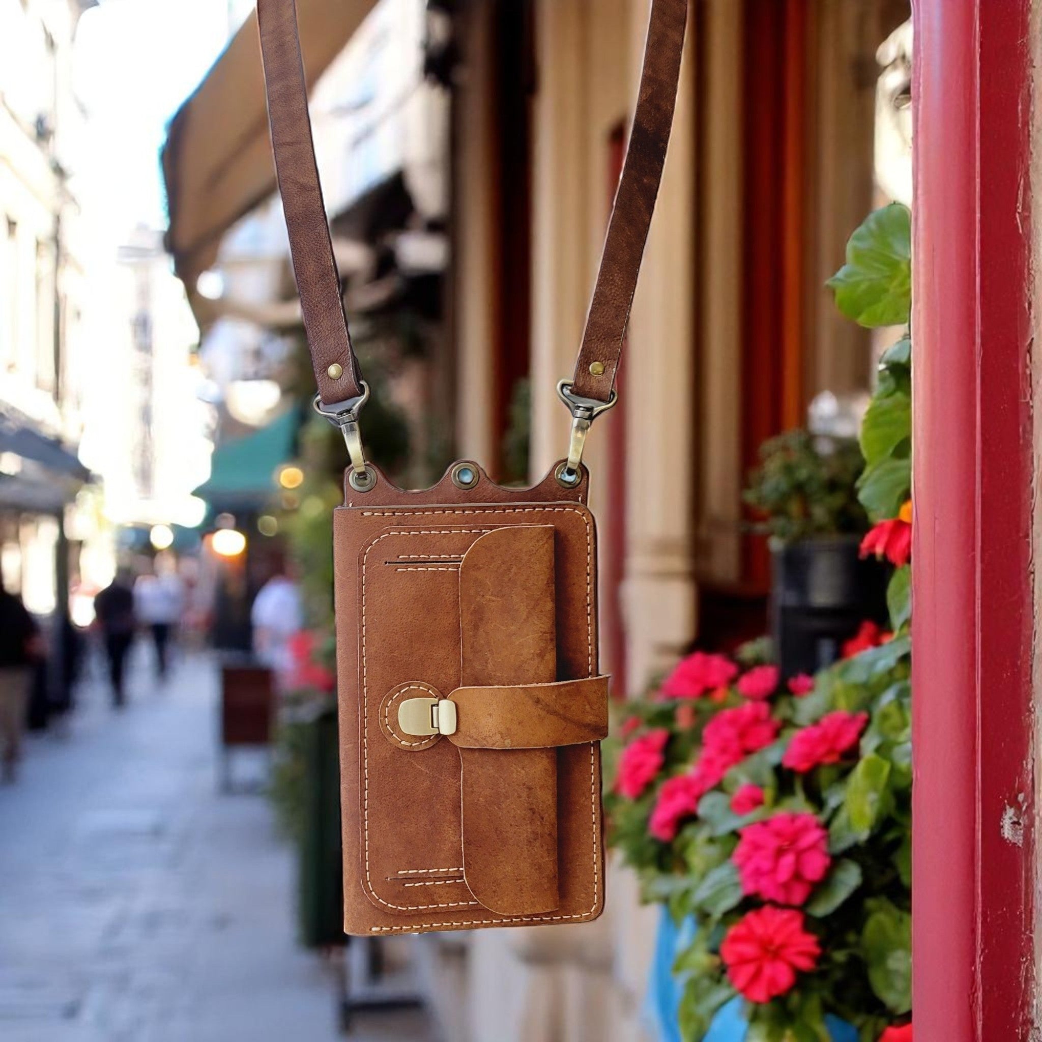 Brown leather crossbody bag with a blurred street scene in the background