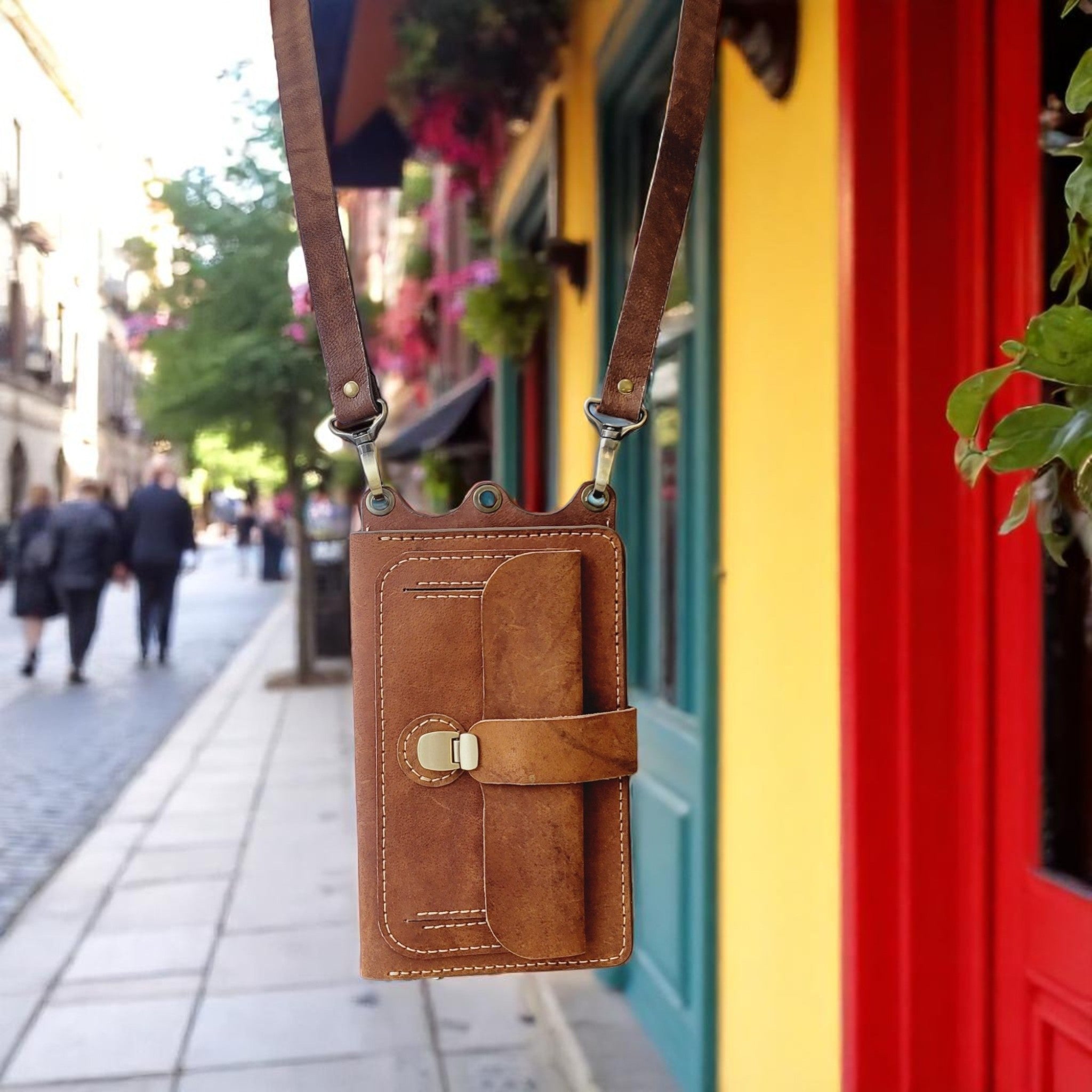 Brown leather crossbody bag with a blurred street scene in the background