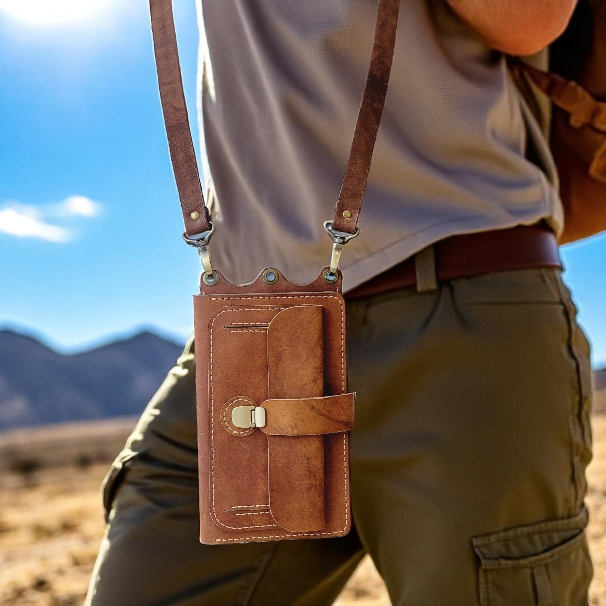 Person wearing a brown leather crossbody bag with a desert landscape in the background