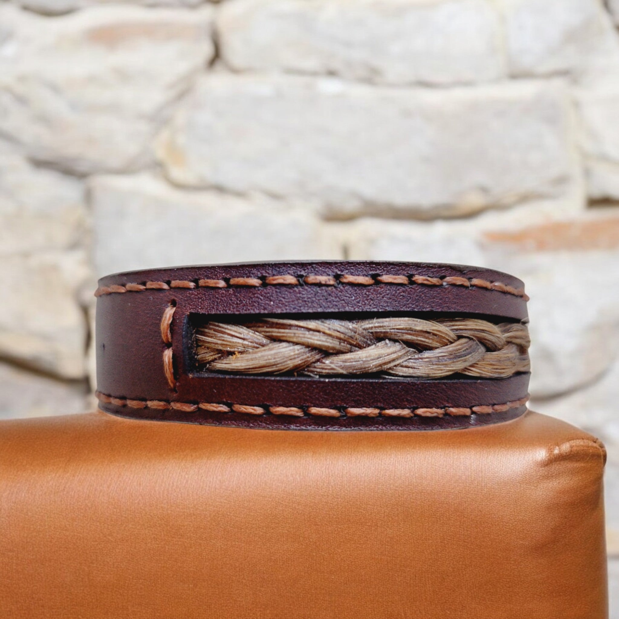 Close‑up of the Lifebraid V1 leather bracelet featuring a discreet braided hair strand set into a hand‑stitched leather band.