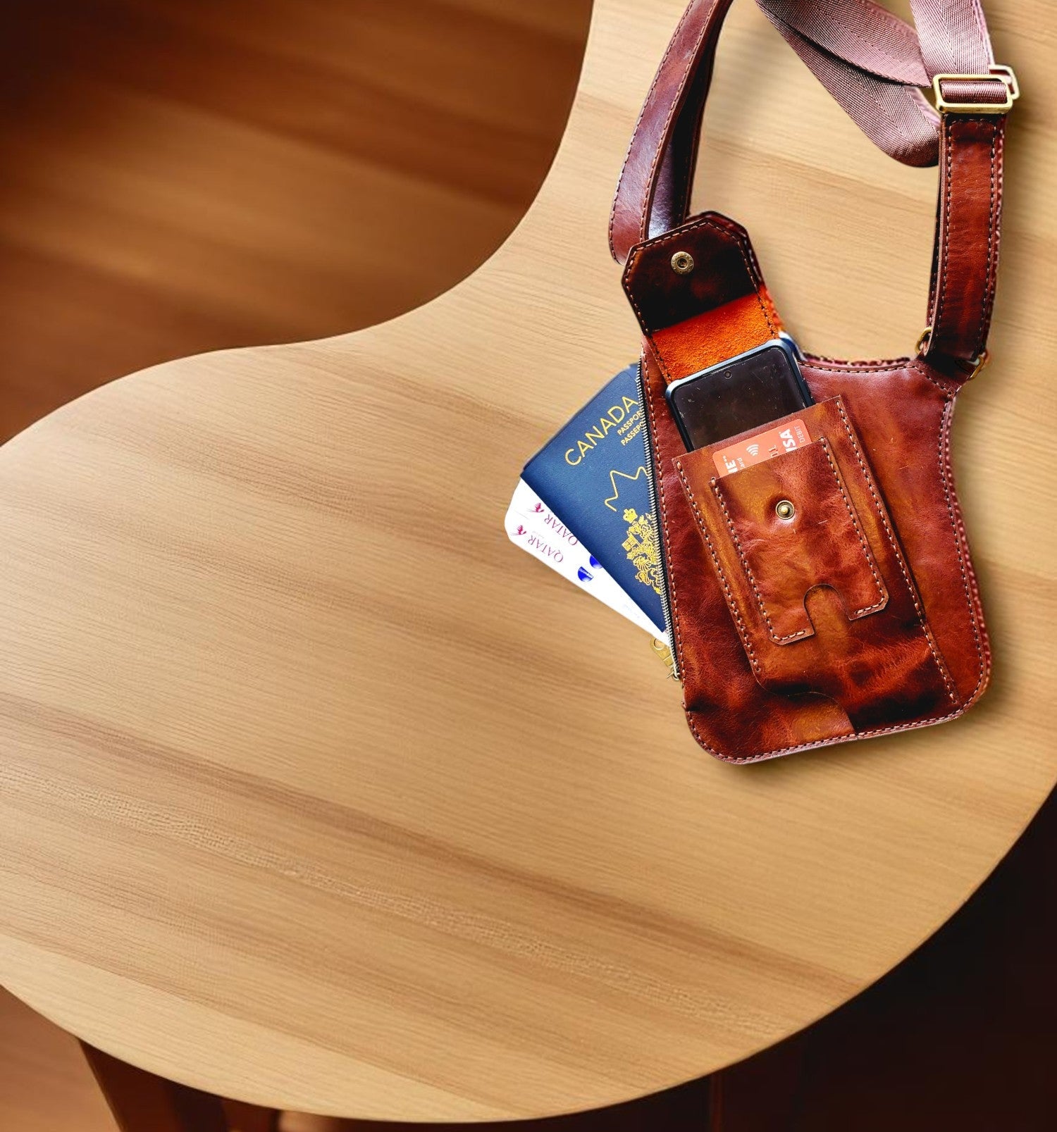 Brown leather pouch with a strap on a wooden surface