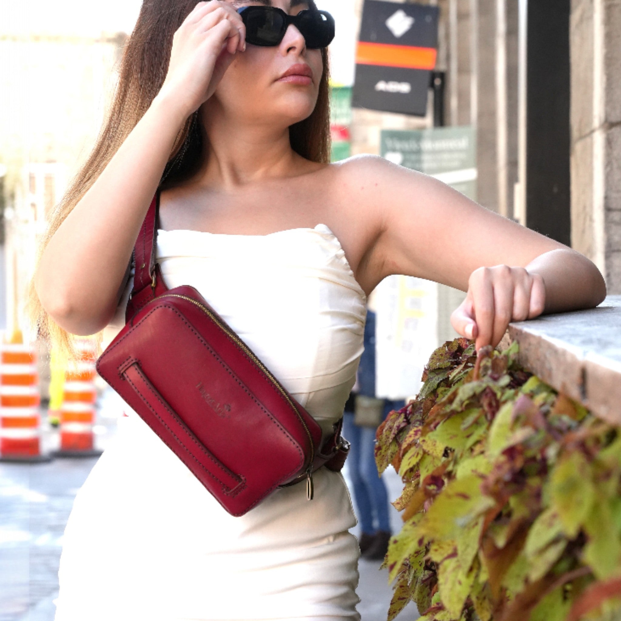 Woman with a red shoulder bag and sunglasses in an urban setting