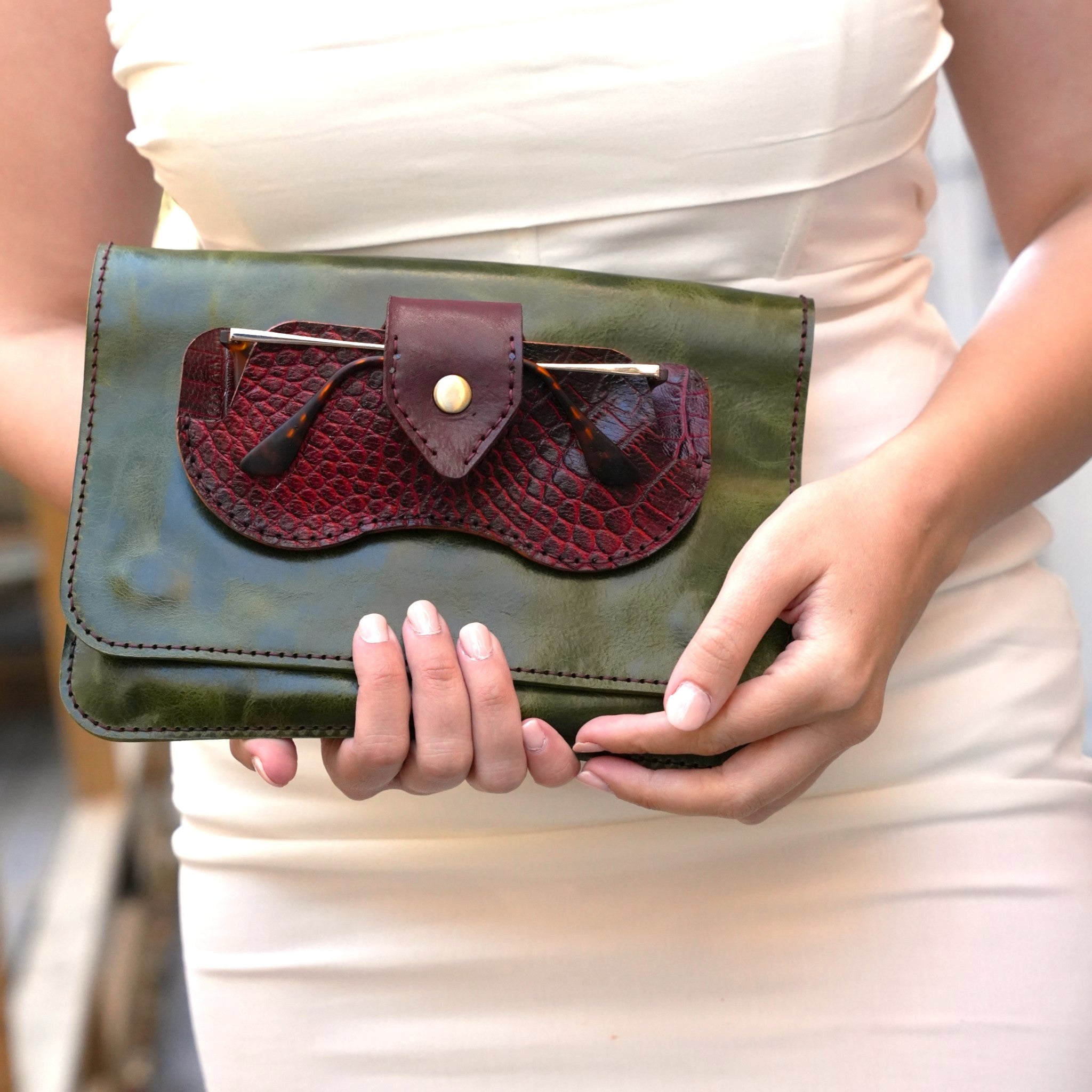 Person holding a green clutch with a maroon flap