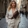Woman in a beige suit with a brown bag walking down a city street.