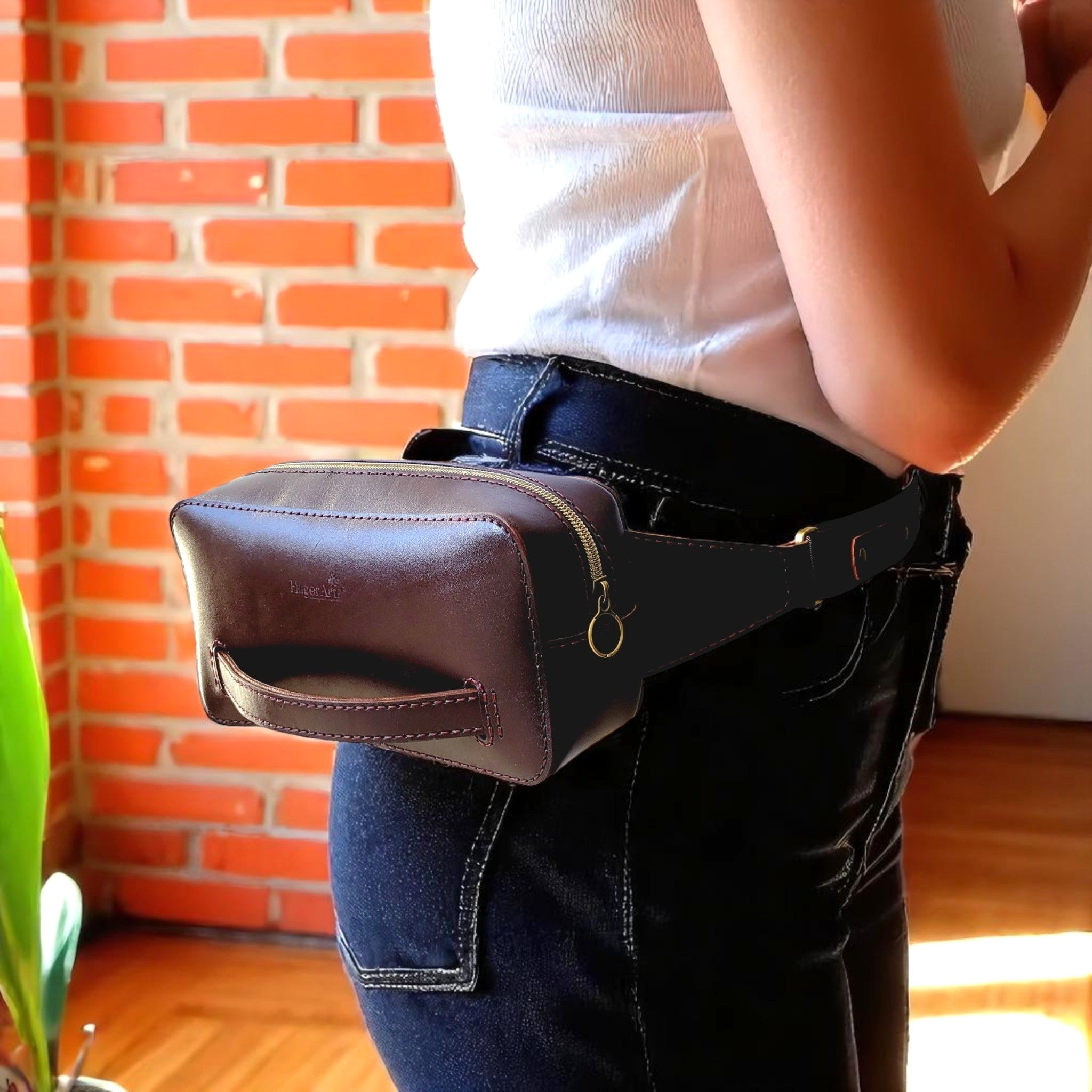 Person wearing a brown leather waist bag with a brick wall background