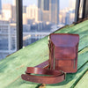 A red leather crossbody bag with multiple compartments and secure zippers, displayed on a wooden bench.