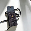 Black crocodile-patterned handbag with a strap on a light background