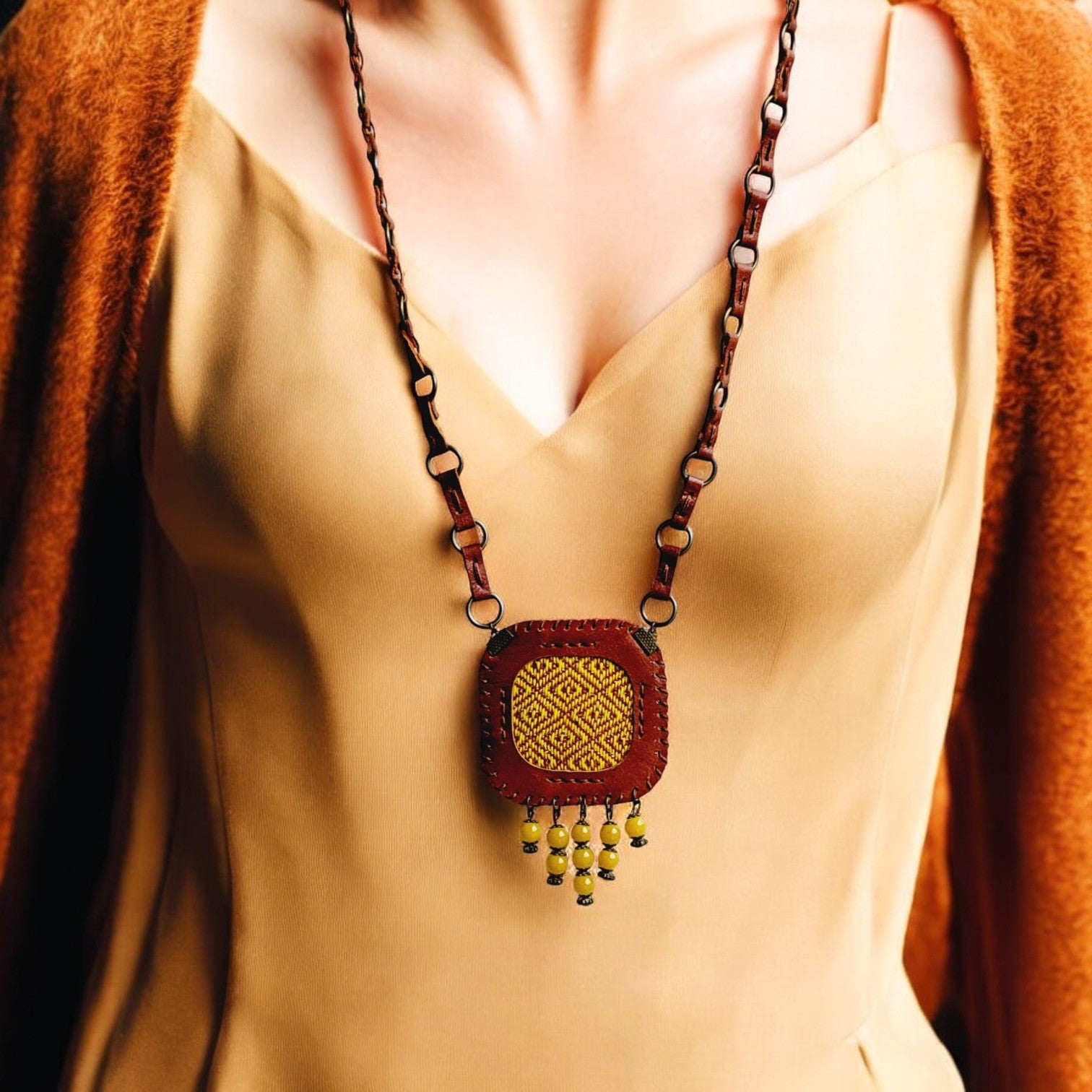 “Velora C3 handmade leather and handwoven-fabric pendant necklace in honey with yellow bead fringe.”