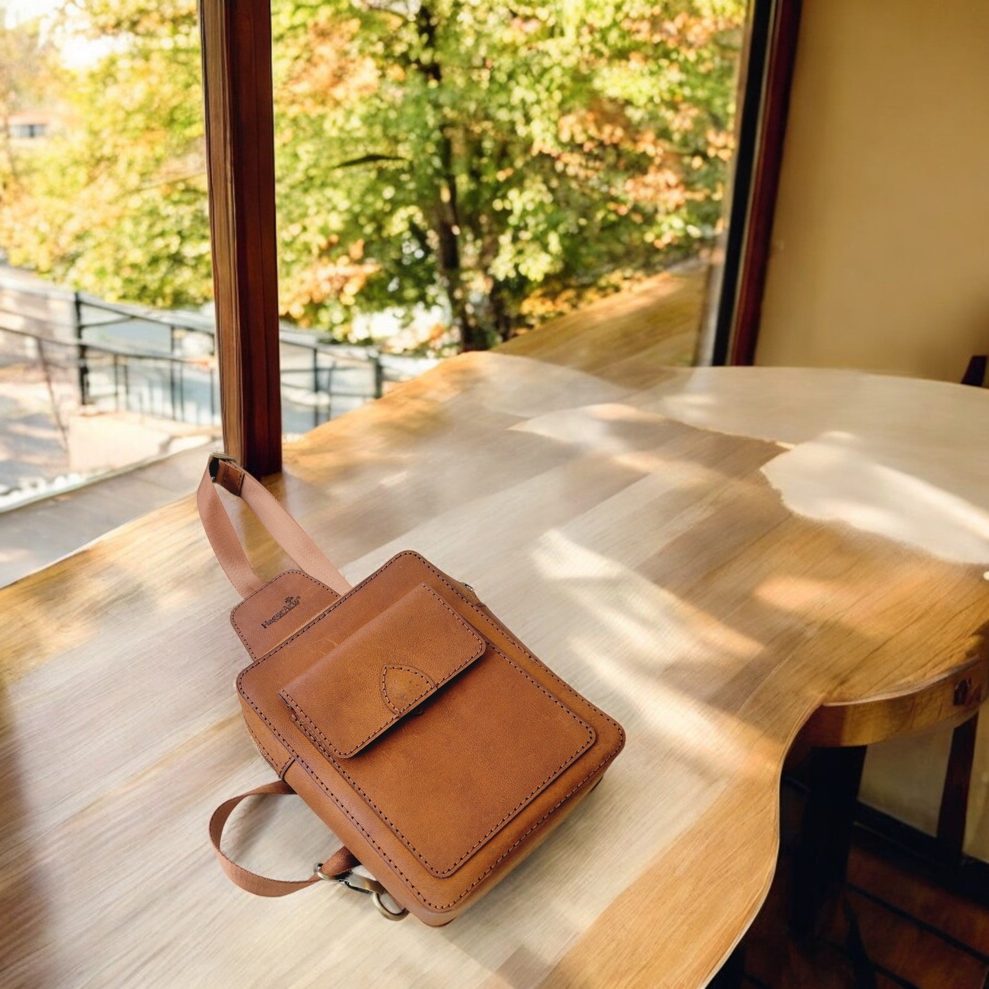 Odyssey C1 tan handmade leather sling bag worn crossbody, top zip and front flap pocket.