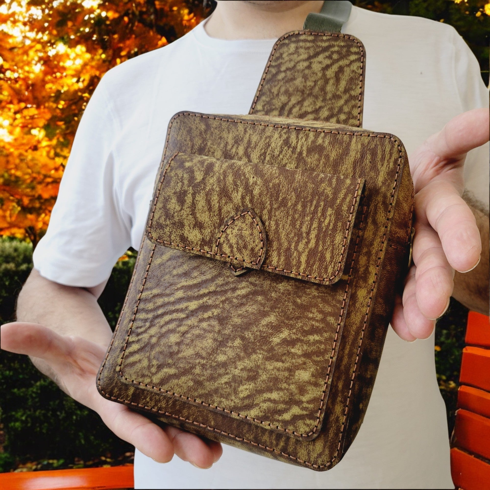 Side view of textured camel-leather sling showing adjustable strap and back zipper pocket — HagorArts Odyssey C2.