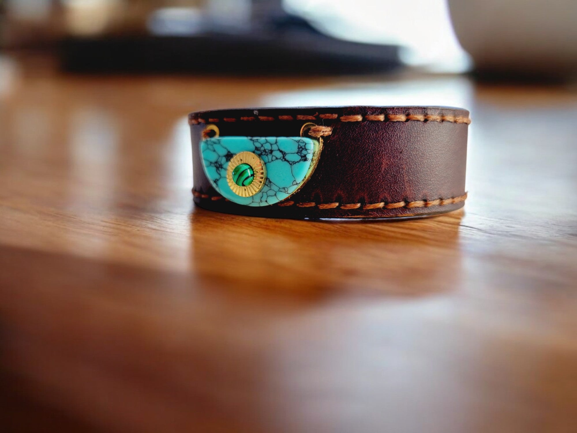 Close-up of a hand wearing the Orbis M1 leather bracelet in dark full-grain leather, featuring a distinctive handcrafted centerpiece and fine hand-stitched detailing.