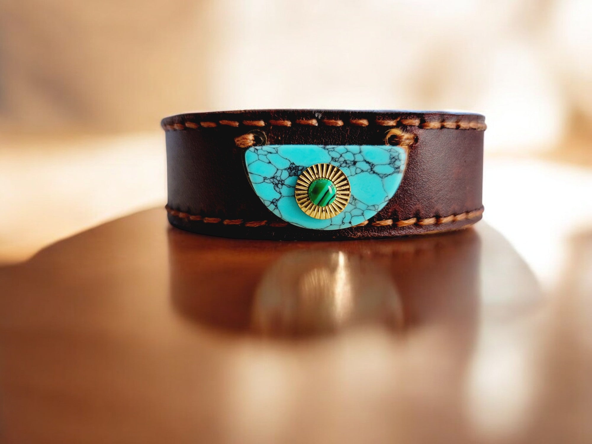 A brown leather bracelet with a semi-precious central stone, set in a premium leather bracelet, on a wooden surface.