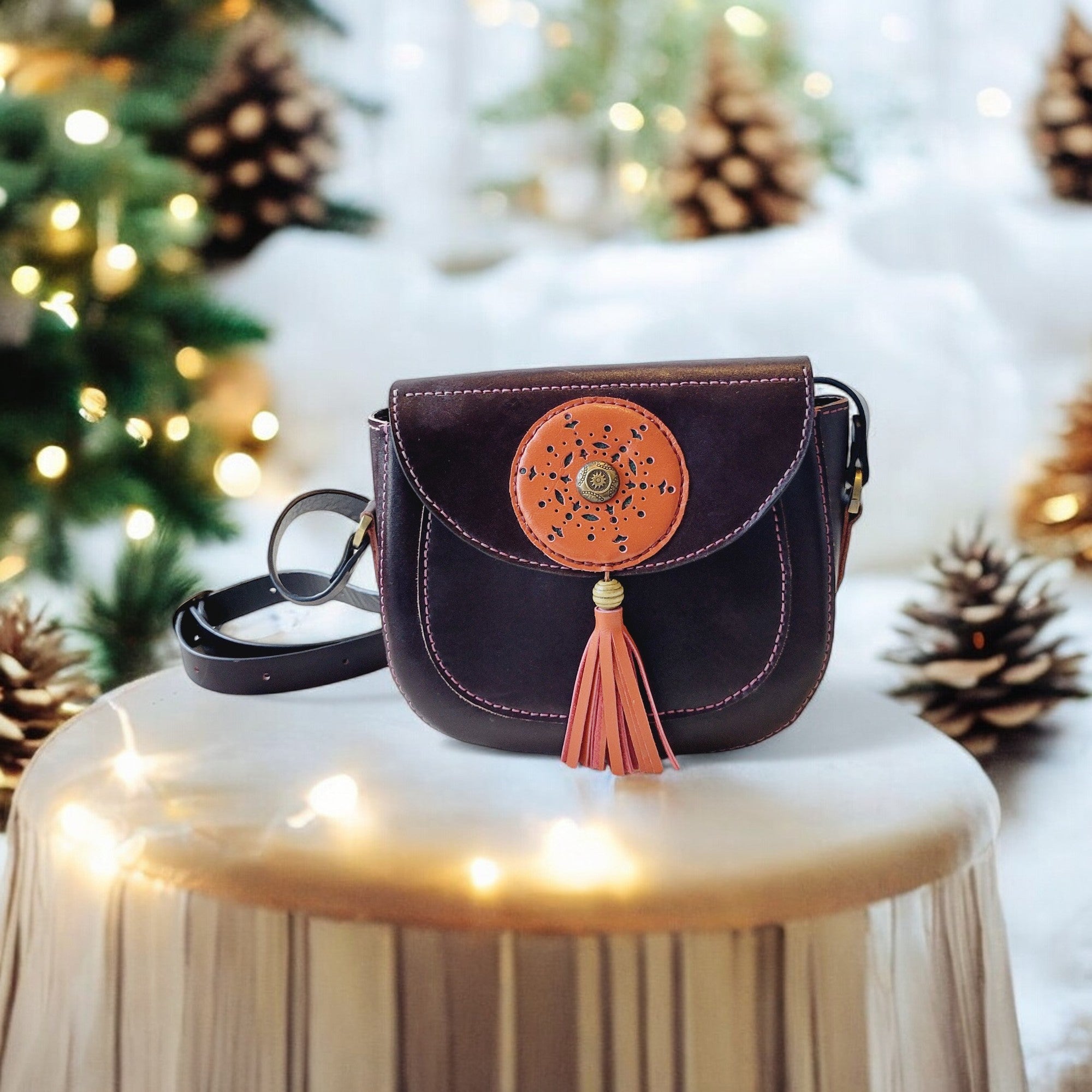 Perforated tangerine medallion hand-cut and set over the flap; antique-brass hardware accents.